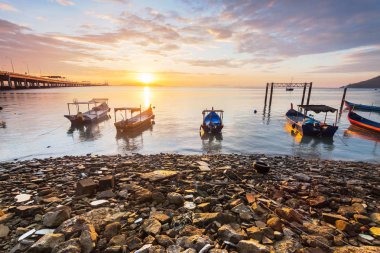Balıkçı teknesi ile gündoğumu kayalık sahil 
