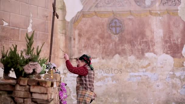Женщина зажигает молитвенную свечу в заброшенной церкви — стоковое видео