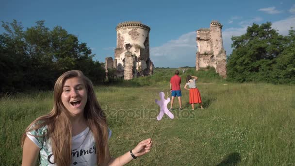 Jovem mulher loira bonita fala com câmera - parque com castelo no fundo — Vídeo de Stock