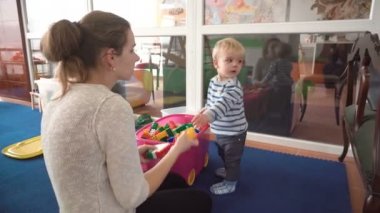 Onun bebek çocuk renkli bloklar, toplar, mutfak oda ile oynarken annesi