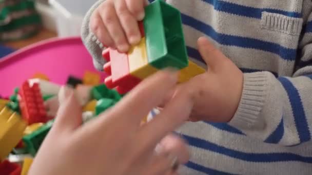 Mother playing with her baby boy in room with colourful blocks, balls, kitchen — Stock Video