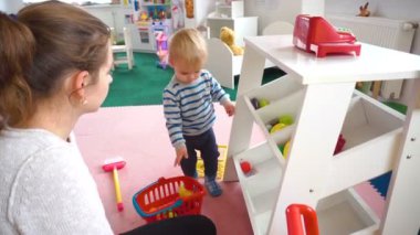 Onun bebek çocuk renkli bloklar, toplar, mutfak oda ile oynarken annesi