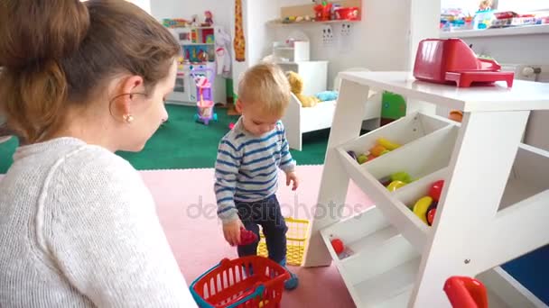 Madre jugando con su bebé en la habitación con bloques de colores, bolas, cocina — Vídeo de stock