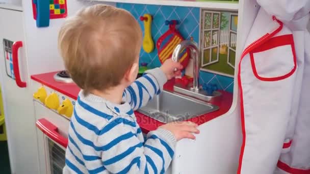Μητέρα, παίζοντας με το αγόρι της το μωρό στο δωμάτιο με τα πολύχρωμα μπλοκ, μπάλες, κουζίνα — Αρχείο Βίντεο