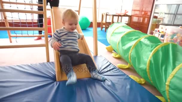 Moeder speelt met haar babyjongen in een kamer met kleurrijke blokken, ballen, keuken — Stockvideo