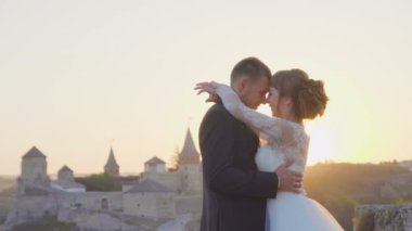 Güzel düğün çift birbirlerine öpücük ve kalenin günbatımı 4 k kucaklayan