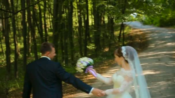 Boldog menyasszony és a vőlegény a csinos lány átölelve és megcsókolta az erdő — Stock videók