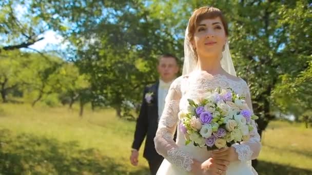 Жених дает невесте букет ее стоя на одном колене на природе — стоковое видео