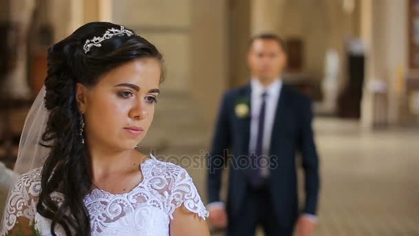 Elegante bruid en bruidegom dragen blauwe pak hand in hand wandelen in oude kerk — Stockvideo