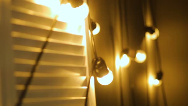 Lâmpadas de grinalda perto. Lâmpada elétrica brilhar pendurado na parede como decoração — Vídeo de Stock