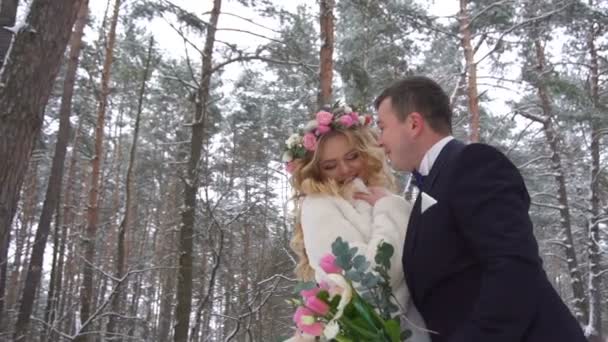 Jovem casal caminhando na floresta de inverno de mãos dadas e abraçando em câmera lenta — Vídeo de Stock