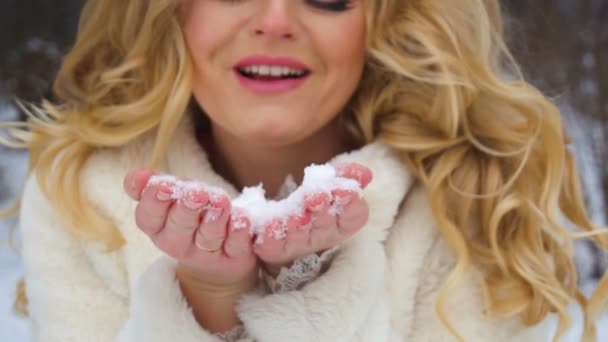 Slow motion of winter blond lady blowing a handful of snow right in the camera — Stock Video