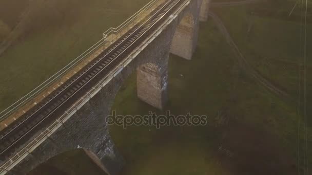 Tiro aéreo da ponte ferroviária de pedra no por do sol com sombra interessante 4k — Vídeo de Stock