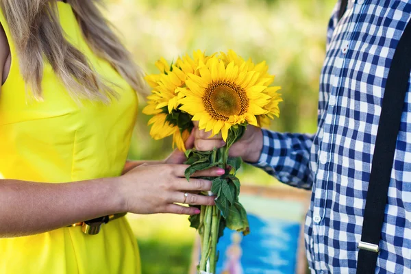 Young man gives a bouquet of sunflowers — Stockfoto