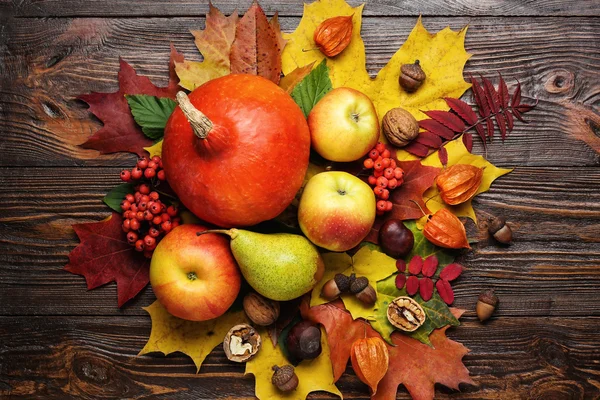 autumn still life, harvested pumpkins with fall leaves and autumn fruit, gifts of autumn, wooden background, walnuts, maple leaves - autumn composition from top.