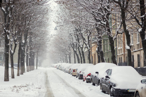 Snow-covered street in Lviv. Snowfall, car covered with snow. Lviv, Ukraine
