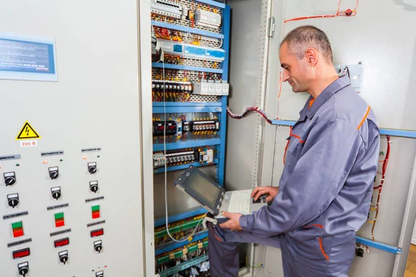 electrician testing industrial machine, electrician builder engineer screwing equipment in fuse box, Male Electrician