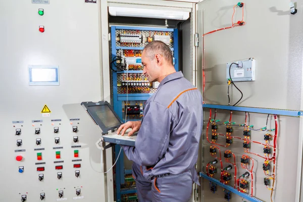 electrician testing industrial machine, electrician builder engineer screwing equipment in fuse box, Male Electrician