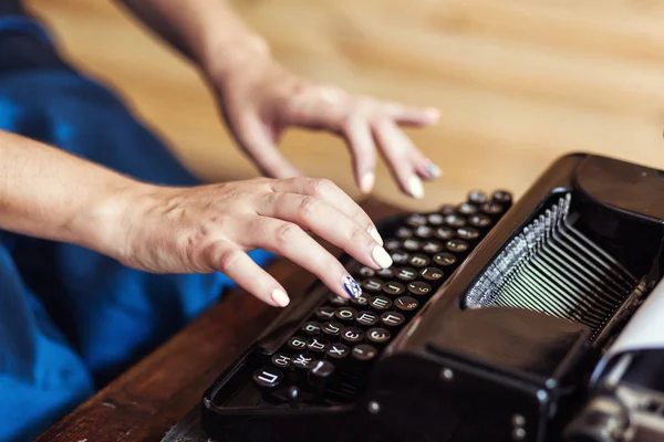 Woman typing on the typewriter, closeup. Fingers on the keys of a typewriter. Vintage typewriter