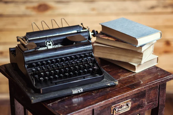 Máquina de escribir y libros sobre la mesa, máquina de escribir vintage y libros antiguos, vintage, área de escritor, máquina de escribir, máquina de escribir vieja con papel en blanco en escritorio de madera, llaves de máquina de escribir vieja, antigüedades, retro —  Fotos de Stock