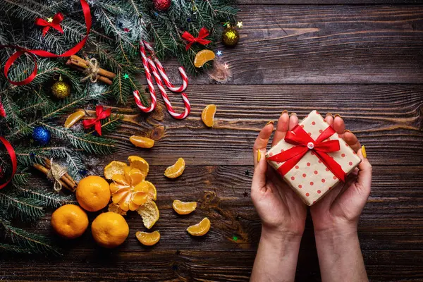 Fondo de madera de Navidad con abeto de nieve. Vista con espacio para copias.Rama de árbol de Navidad con decoraciones sobre fondo de madera. Concepto navideño. Regalos de Navidad en las manos de una chica de cerca — Foto de Stock