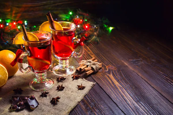 Dos copas, taza de vino caliente rojo drink.Mulled sobre fondo de madera con especias de Navidad, rebanada de naranja, close up. — Foto de Stock