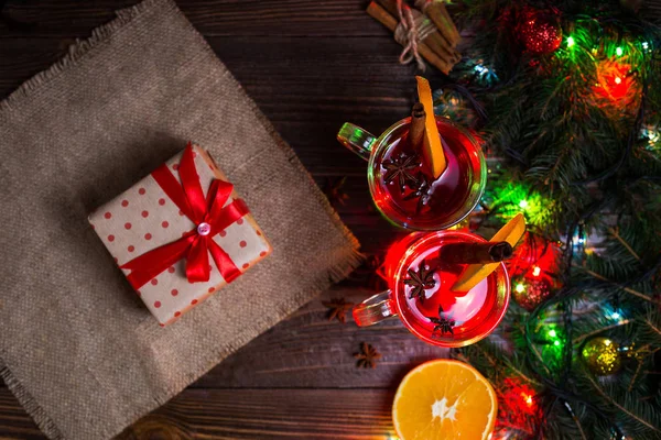 Deux verres, tasse de boisson chaude rouge.Vin chaud sur fond en bois avec épices de Noël, tranche d'orange, fermer. Vin chaud de Noël. Branche de l'arbre de Noël, lumières de Noël, espace de copie — Photo