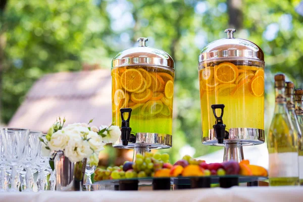 Fruity lemonade, fruit refreshing drink, orange juice, catering, glasses for wine or champagne,exit buffet, Lemonade in glass barrels — Stock Photo, Image