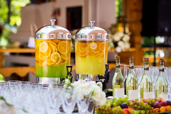 Fruity lemonade, fruit refreshing drink, orange juice, catering, glasses for wine or champagne,exit buffet, Lemonade in glass barrels — Stock Photo, Image