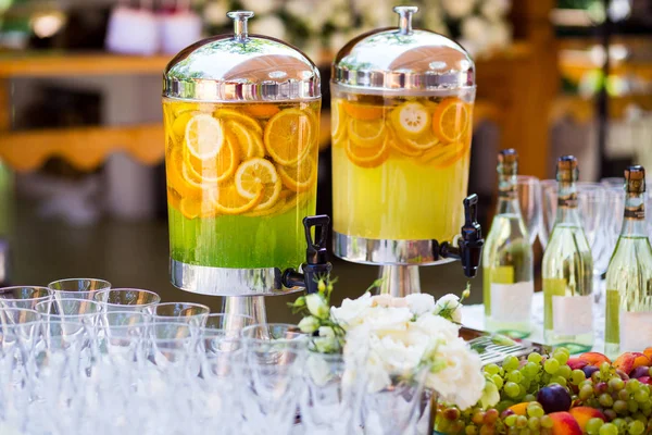 Fruity lemonade, fruit refreshing drink, orange juice, catering, glasses for wine or champagne,exit buffet, Lemonade in glass barrels — Stock Photo, Image