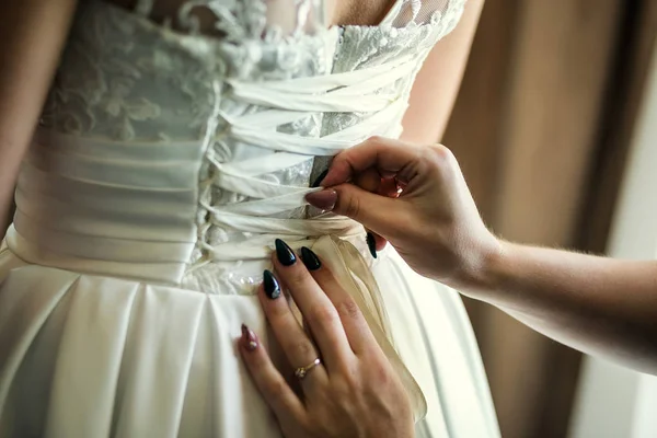Ráno nevěsty, nevěsty nosí šaty, družička opraví luk na šaty, svatba, krásné šaty — Stock fotografie