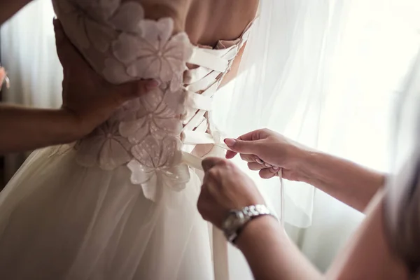 La mañana de la novia, la novia lleva el vestido, la dama de honor corrige el arco en el vestido, la boda, el vestido hermoso — Foto de Stock