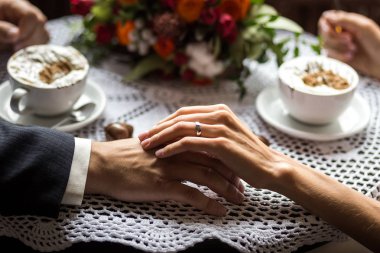 çift elele çift içme kahve bir kafede, sevgi dolu bir kafe, bir güzel buket, kahve çikolata şekerleme ile yakın çekim toplantıda eller