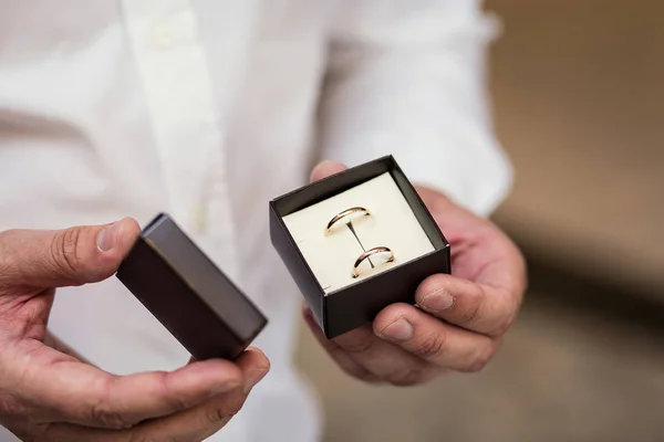 Bräutigam hält Trauringe, Trauringe liegen in der klassischen Hochzeitsbox, Brautzubehör, Europäische Hochzeit, Amerikanische Hochzeit — Stockfoto