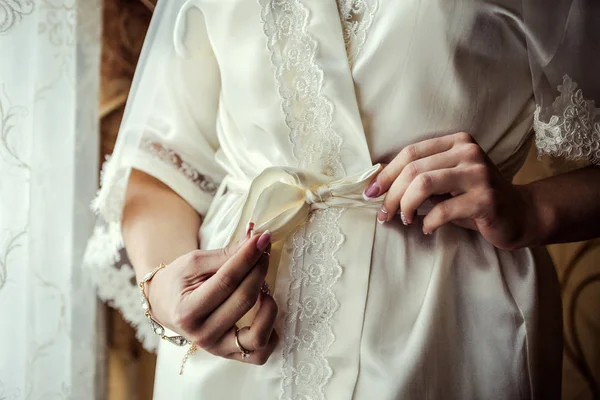 Mañana de la novia, la novia lleva un vestido, una boda, un hermoso vestido, una chica con un bata blanca en la ventana, la chica ata el cinturón en la bata —  Fotos de Stock