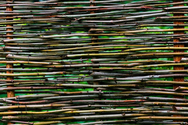 Textuur van geweven wijnstokken, Detail van een nieuwe rieten hek geen nagels, rieten rustieke hek in de zomertuin op gras achtergrond, omheining van geweven wilg twijgen — Stockfoto