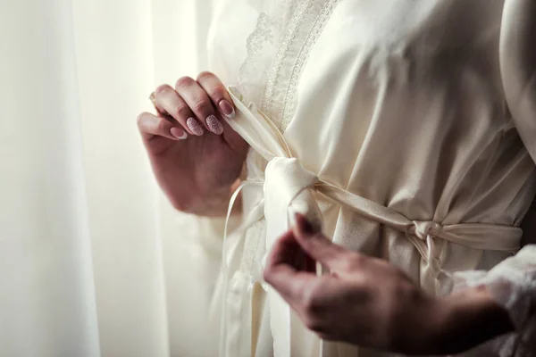 Mañana de la novia, la novia lleva un vestido, una boda, un hermoso vestido, chica en un bata blanca en la ventana, la chica ata el cinturón en la bata, concepto de boda, concepto de mujer, concepto de belleza — Foto de Stock