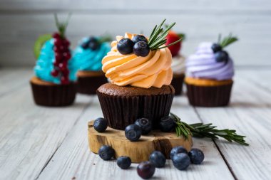 Çikolatalı kek. Cupcakes. Meyveler, meyve, çilek ile cupcakes. En çok view.colorful kek, lezzetli kek, renkli krem, ahşap arka plan üzerinde yaz meyveleri ile cupcakes, tatlı kavramı, kapatmak