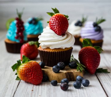 Çikolatalı kek. Cupcakes. Meyveler, meyve, çilek ile cupcakes. En çok view.colorful kek, lezzetli kek, renkli krem, ahşap arka plan üzerinde yaz meyveleri ile cupcakes, tatlı kavramı, kapatmak