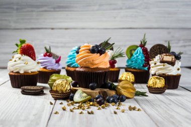 Çikolatalı kek. Cupcakes. Meyveler, meyve, çilek ile cupcakes. En çok view.colorful kek, lezzetli kek, renkli krema, şeker, ahşap arka plan üzerinde yaz meyveleri ile cupcakes, tatlı kavramı, kapatmak