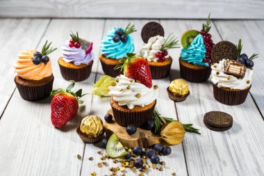 Çikolatalı kek. Cupcakes. Meyveler, meyve, çilek ile cupcakes. En çok view.colorful kek, lezzetli kek, renkli krema, şeker, ahşap arka plan üzerinde yaz meyveleri ile cupcakes, tatlı kavramı, kapatmak
