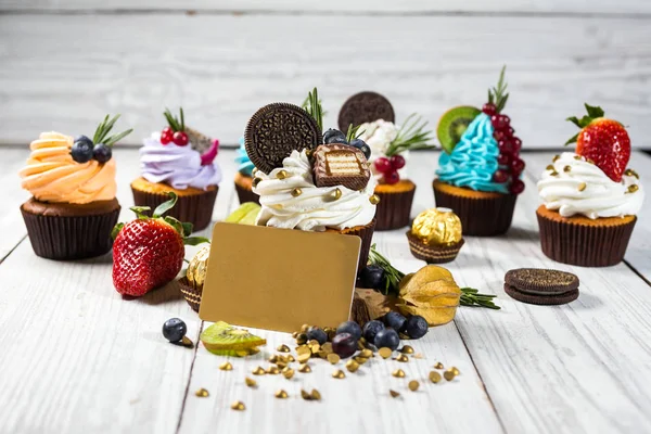 Chocolate cupcakes and cake. Cupcakes with berries,fruit,strawberries. Top view.colorful cupcake,tasty cake,colorful cream,candies,cupcakes with summer berries on wooden background,close up,dessert concept