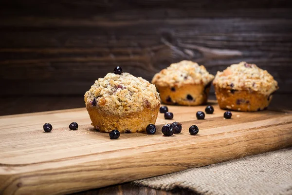 Magdalenas de arándanos recién horneadas con una avena desmenuzada sobre una tabla de madera natural, magdalenas caseras de arándanos, delicioso cupcake con arándanos, concepto del desierto —  Fotos de Stock