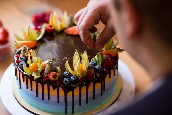 Cukrář v kuchyni zdobí dort z čokolády, ovoce, cukroví, cukrář je zdobení čokoládový dort, vaření třídy, kulinářské, pekařství, jídlo a lidé koncepce — Stock fotografie