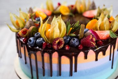 Renkli katmanları ile çikolata cupcakes meyve, çilek ve şeker ile dekore edilmiştir. View.Colorful lezzetli kek, renkli krem, ahşap arka plan top, tatlı kavramı, doğum günü pastası, kapatmak 