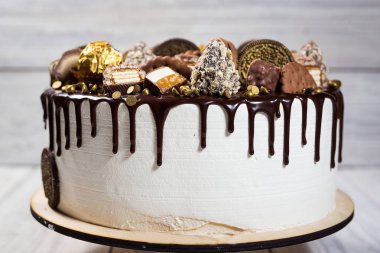 Çikolatalı kek, şeker, kurabiye ve çikolata barları ile dekore edilmiştir. Üstten Görünüm. lezzetli pasta, krem, ahşap renkli arka plan, kapatmak, tatlı kavramı, doğum günü pastası 