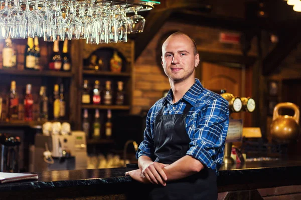 Barman at work in pub,Portrait of cheerful barman worker standing,Waiter giving menus,A pub.Bar.Restaurant.Classic.Evening.European restaurant.European bar.American restaurant.American bar.