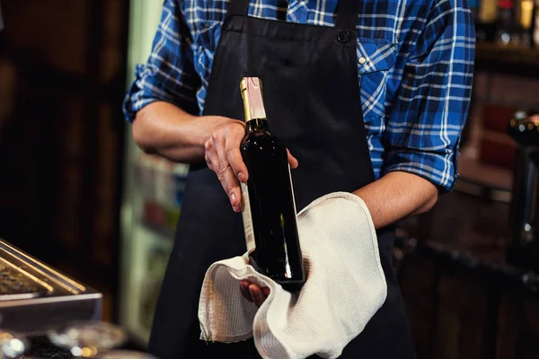 Bartender offers wine,Barman at work in pub,Portrait of cheerful barman worker standing,A pub.Bar.Restaurant.Evening.European restaurant.European bar.American restaurant.American bar.