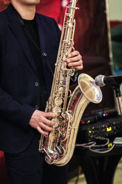 Kırmızı arka planda erkek elinde üzerine lekeleri ile altın saksafon. Müzisyen oyun alto saksafon, portre, elinde el damadın saksafon, caz müzik konsepti üzerinde oynayın.