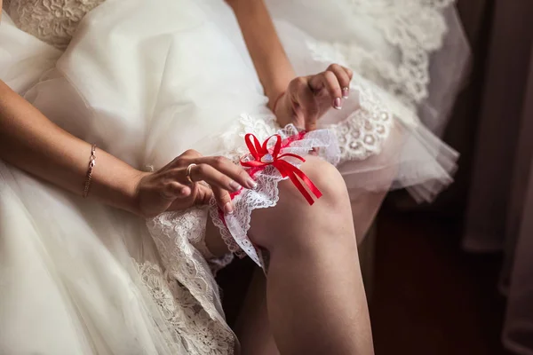 Morning of the bride, the bride wears a wedding garter on leg, a wedding, a beautiful dress — Stock Photo, Image